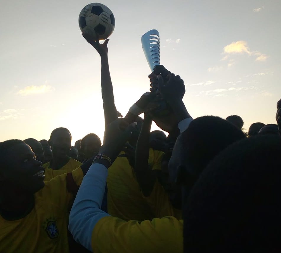 Crowd holding up a football and trophy
