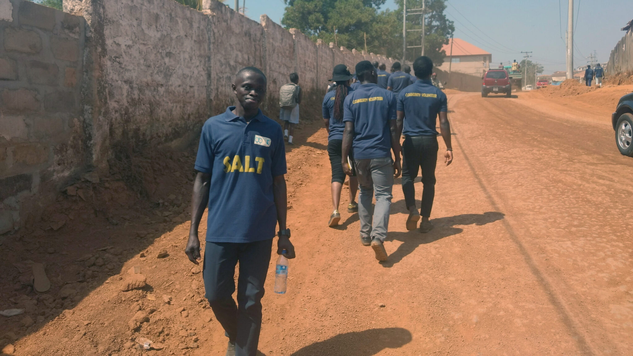 A SALT volunteer turns to smile at the camera as the rest of the team walk towards a village to help a community in need, Sierra Leone