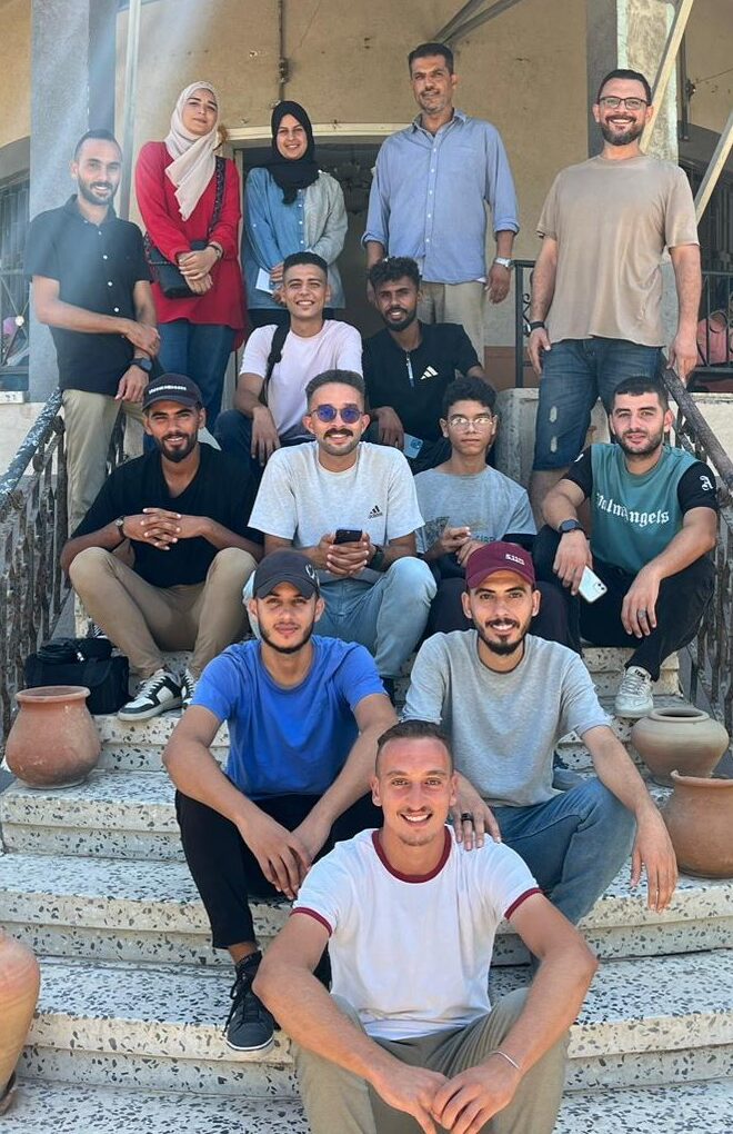 A group of people facing the camera, seated on an outdoor staircase